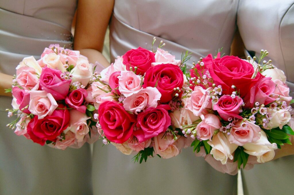 three women holding bouquet of pink and red hybrid tea roses