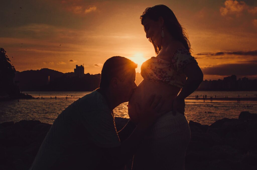 silhouette photography of man kissing belly of a pregnant woman