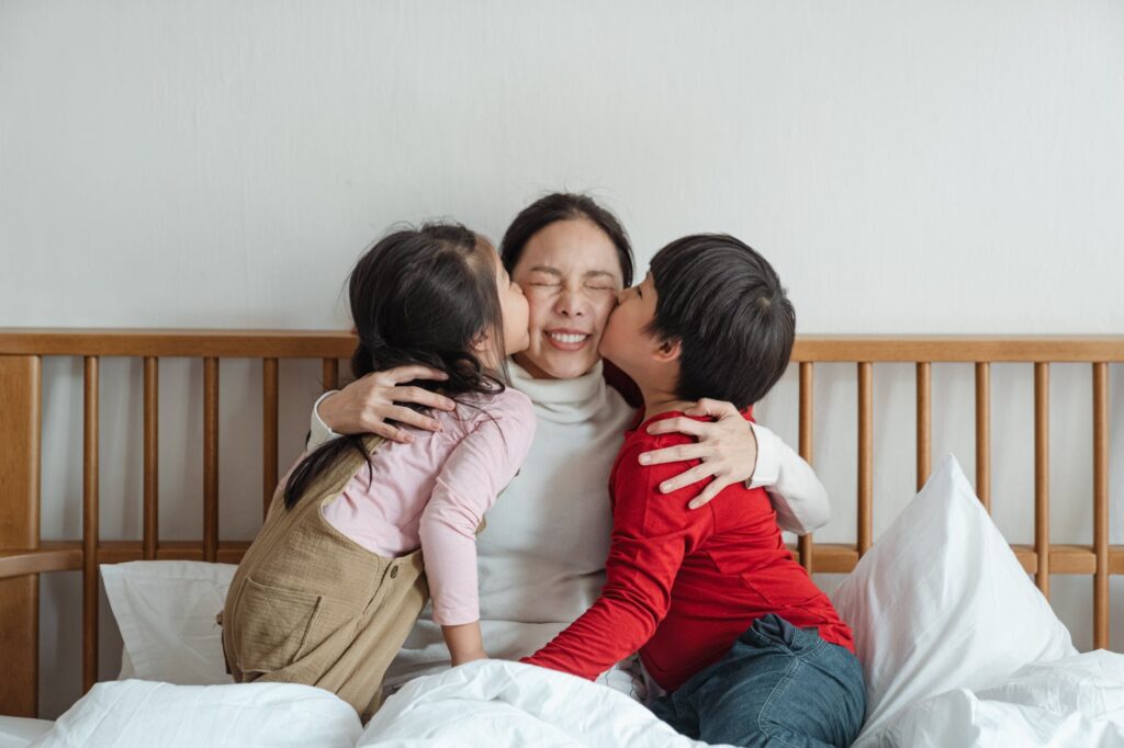 photo of kids kissing their mother