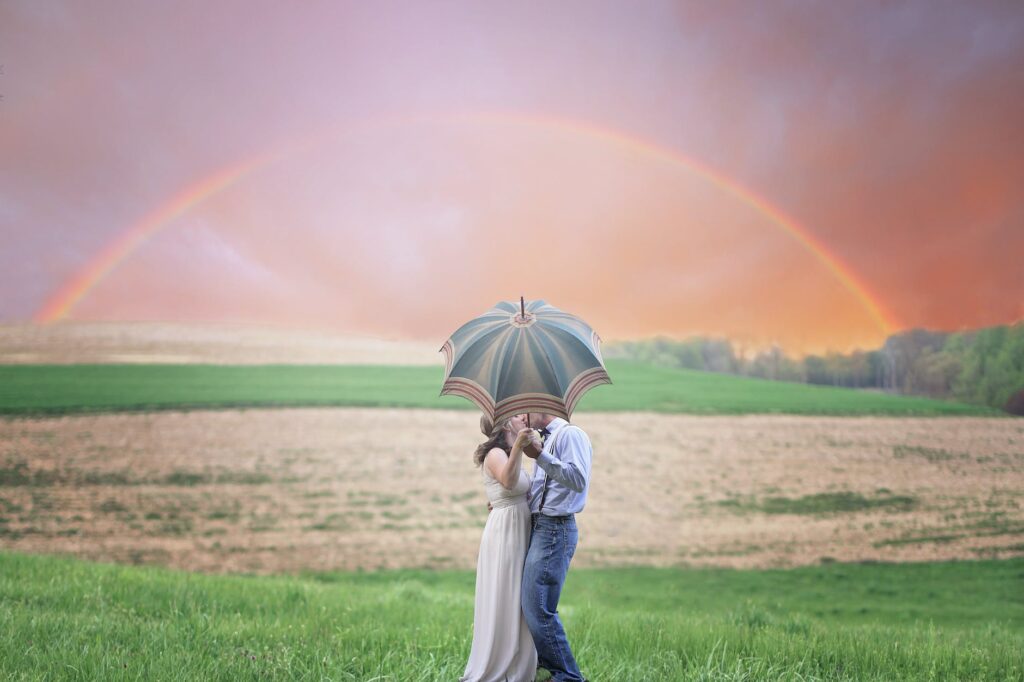 photo of couple holding umbrella while kissing